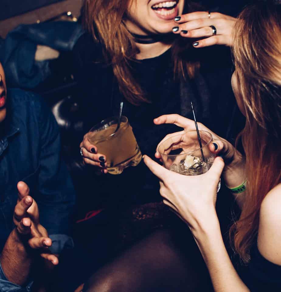Drinking women in a group with glasses in their hands at a party