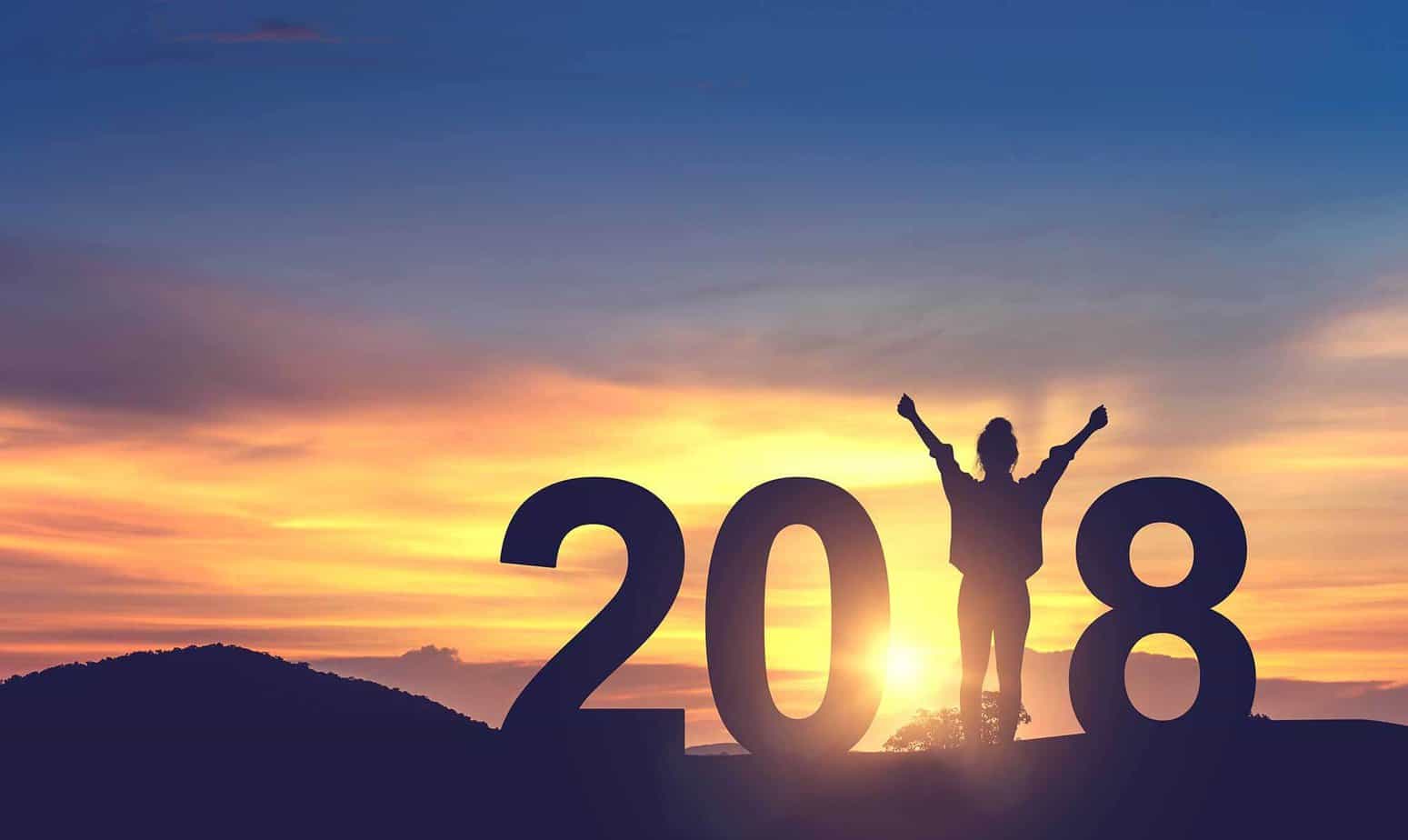 woman raising her arms up in sunset for 2018