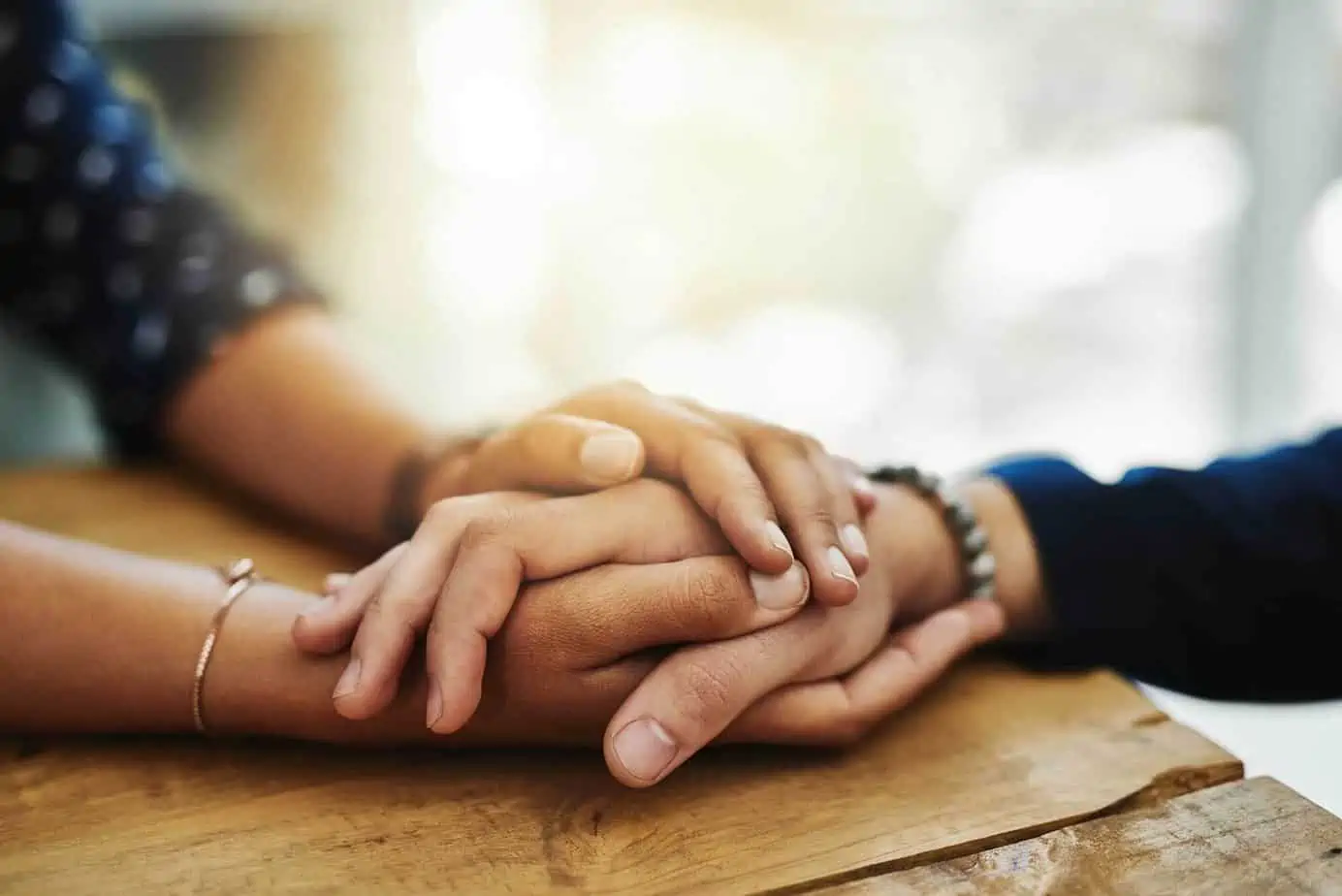A close up of two people holding hands supportively, drug rehab & addiction treatment.