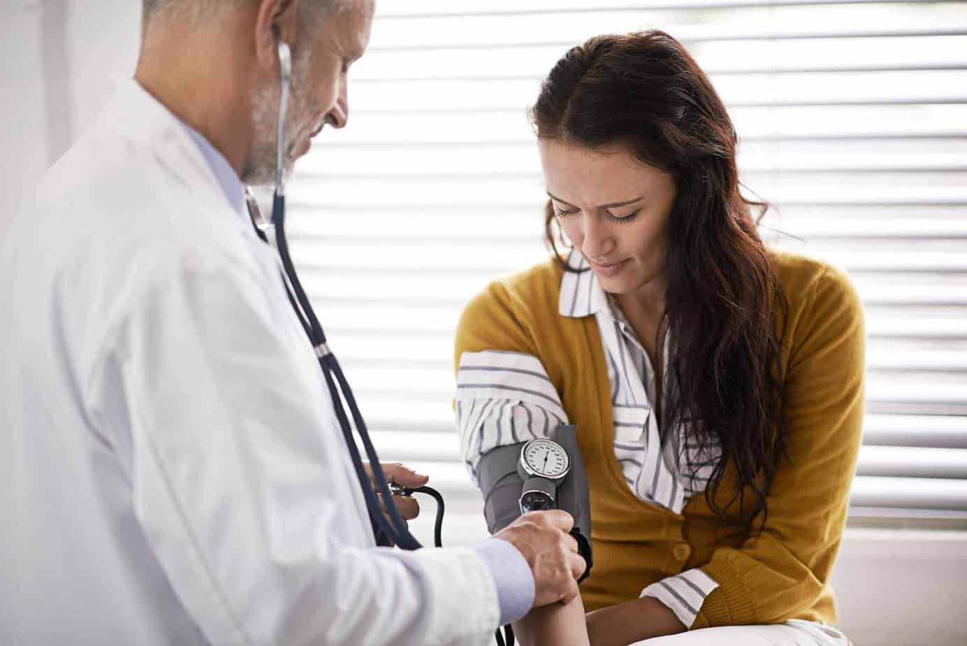 Doctor checking alcoholic’s blood pressure to evaluate the damage addiction has caused.