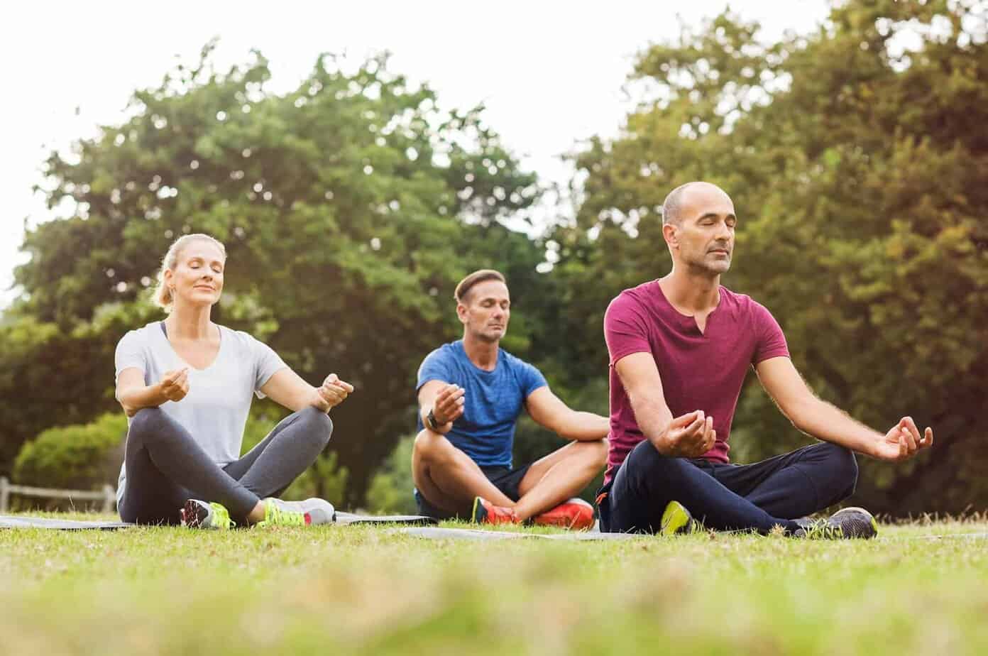 Men and women group outdoor meditation class with legs crossed at Mountainside Canaan location.