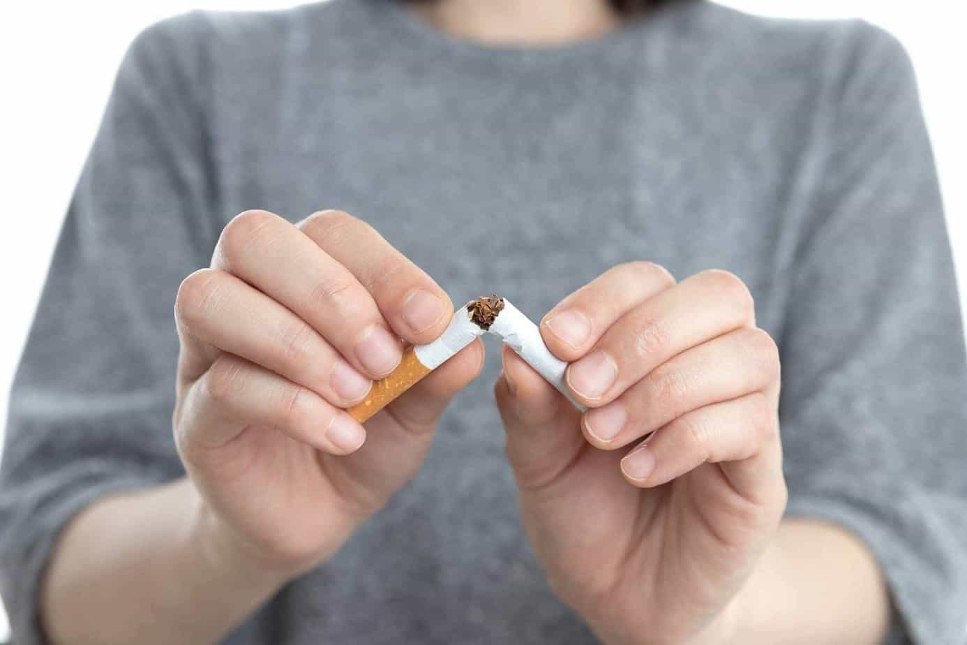A closeup of a woman's hands breaking a cigarette in half.