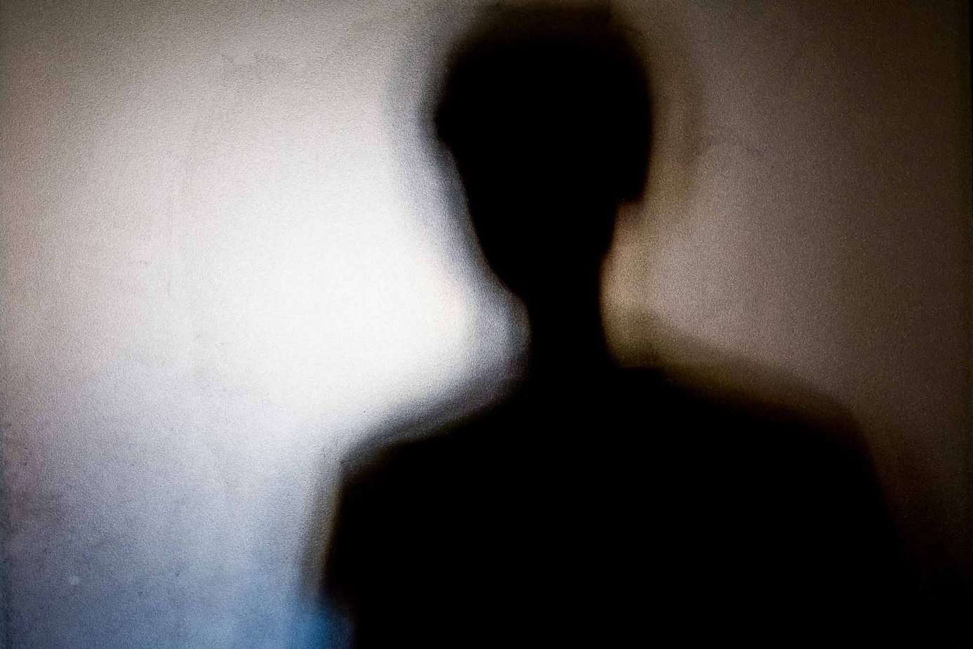 shadow figure of teenage boy in fogged glass