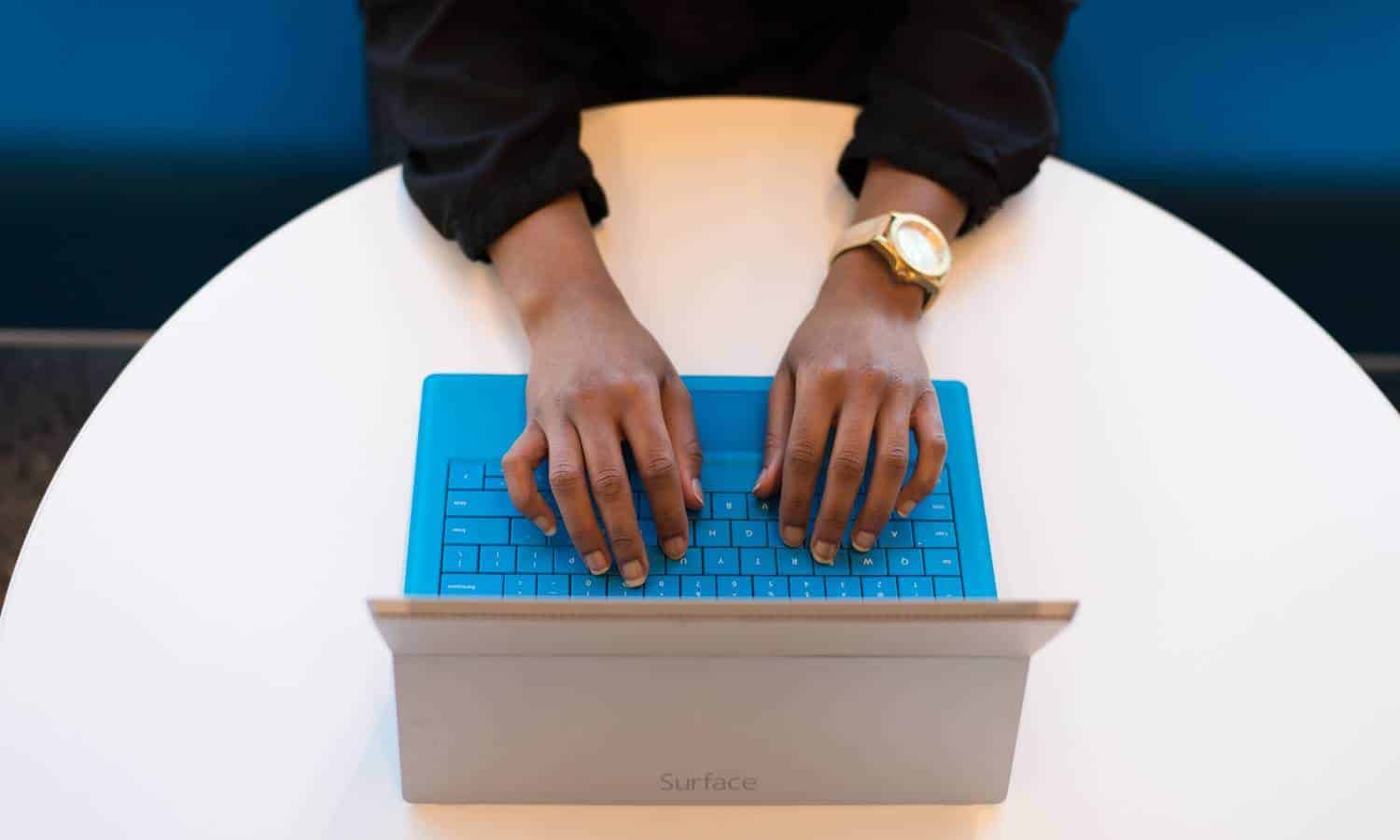 Person typing on blue keyboard to access an addiction treatment virtual support group