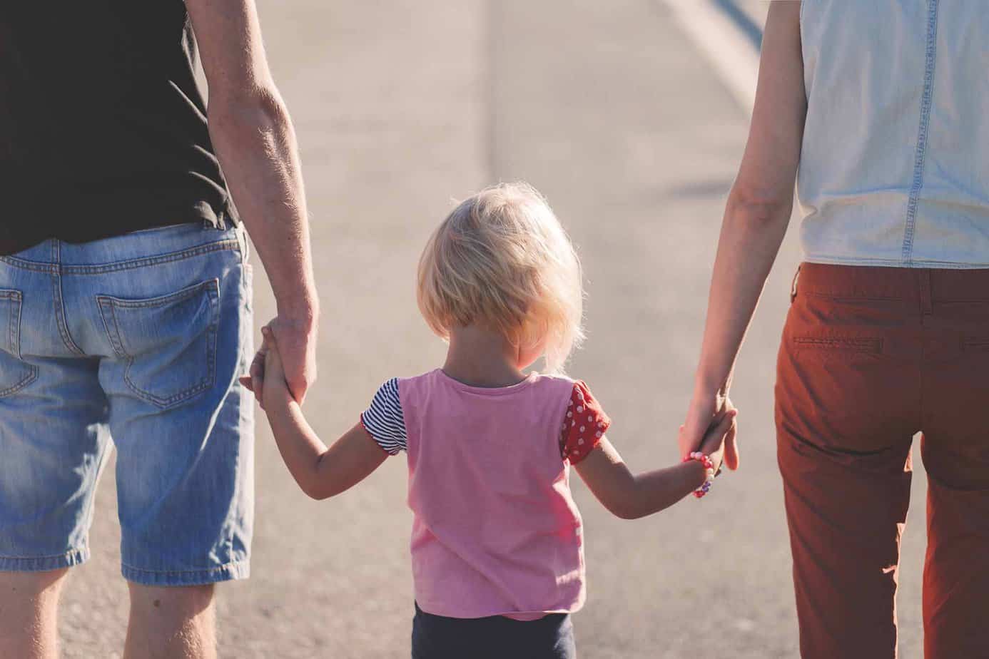 Picture of young family: young parents holding hands with small female child / daughter