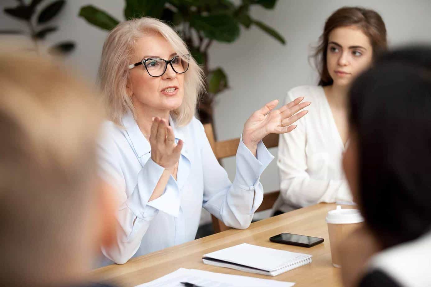 A blonde woman with glasses speaking to other women in a meeting at Mountainside Canaan
