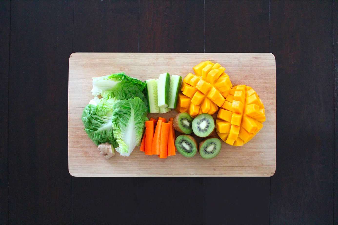 mango, lettuce, kiwi, cucumber, carrots on a cutting board