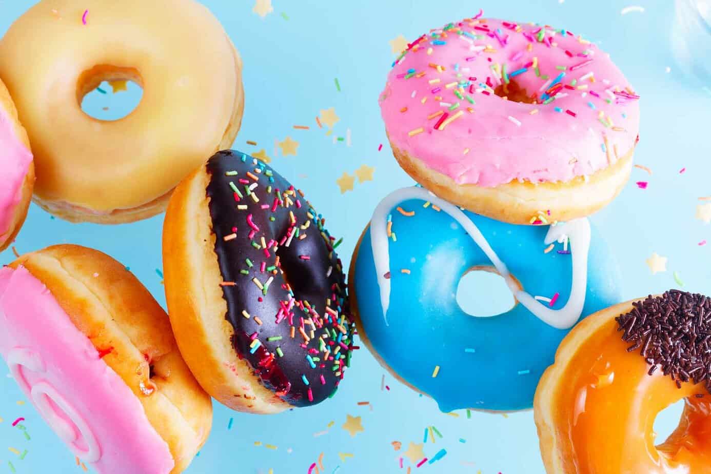 doughnuts of various flavors and toppings behind blue background