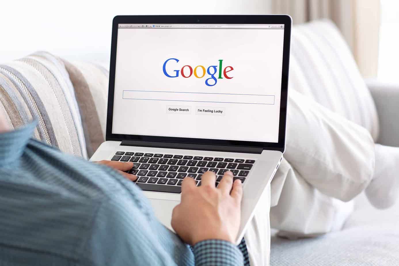 Man lying on couch with google site on laptop