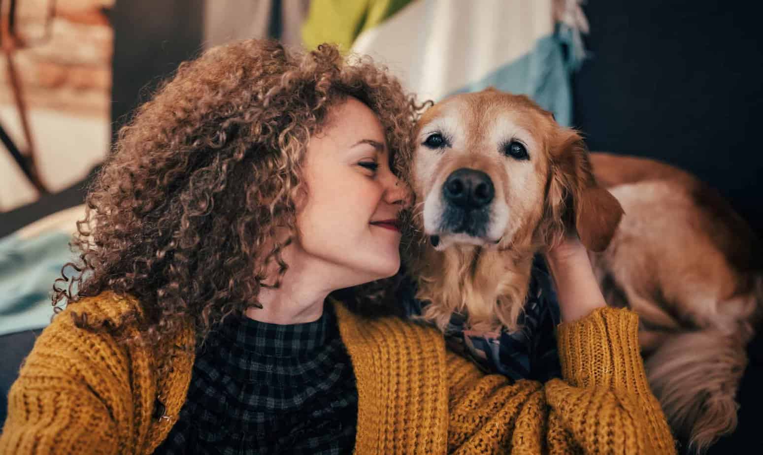 woman in recovery hugging golden retriever dog and smiling