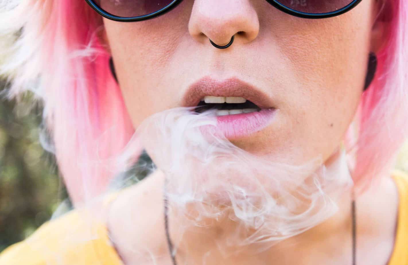 woman with pink hair smoking juul close up