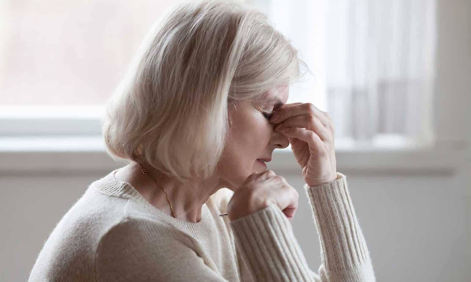 stressed older woman with hands on forehead