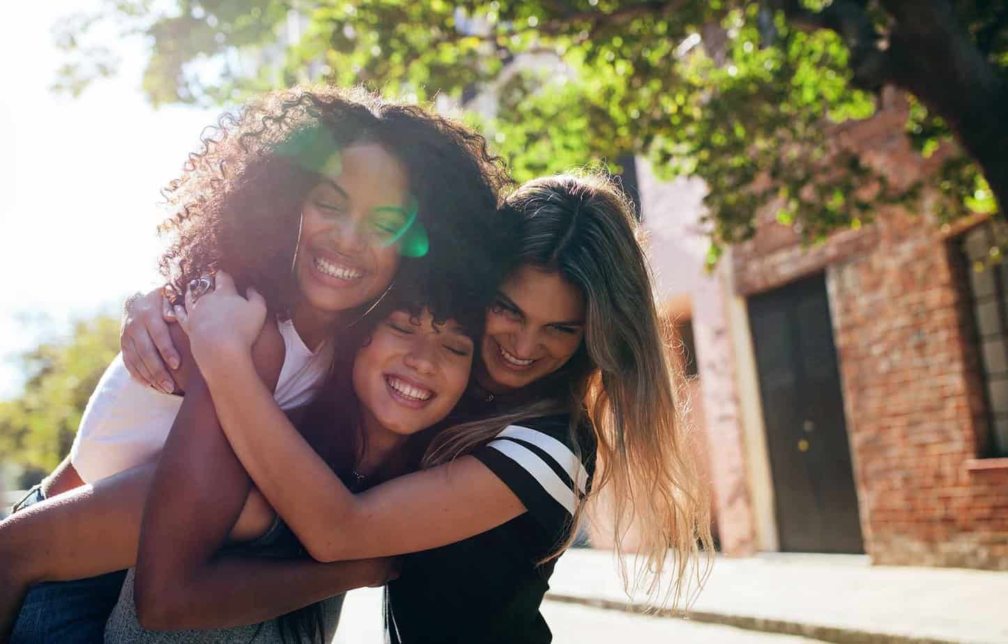 group of females support their friend in addiction recovery by hugging each other outside