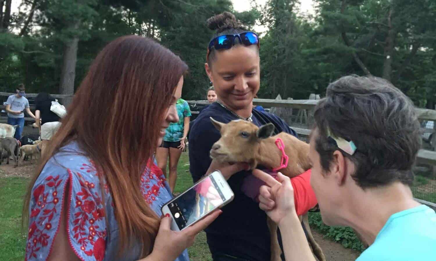 Women petting Baby goat kid at Mountainside Treatment Center Alumni Goat Yoga Therapy in Canaan