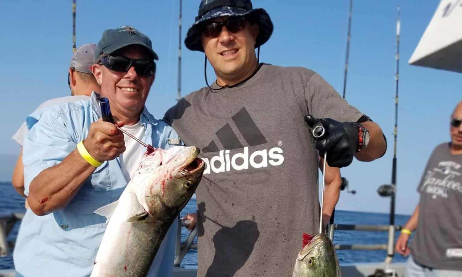 2 men holding fish at Mountainside Treatment Center Alumni Fishing Event