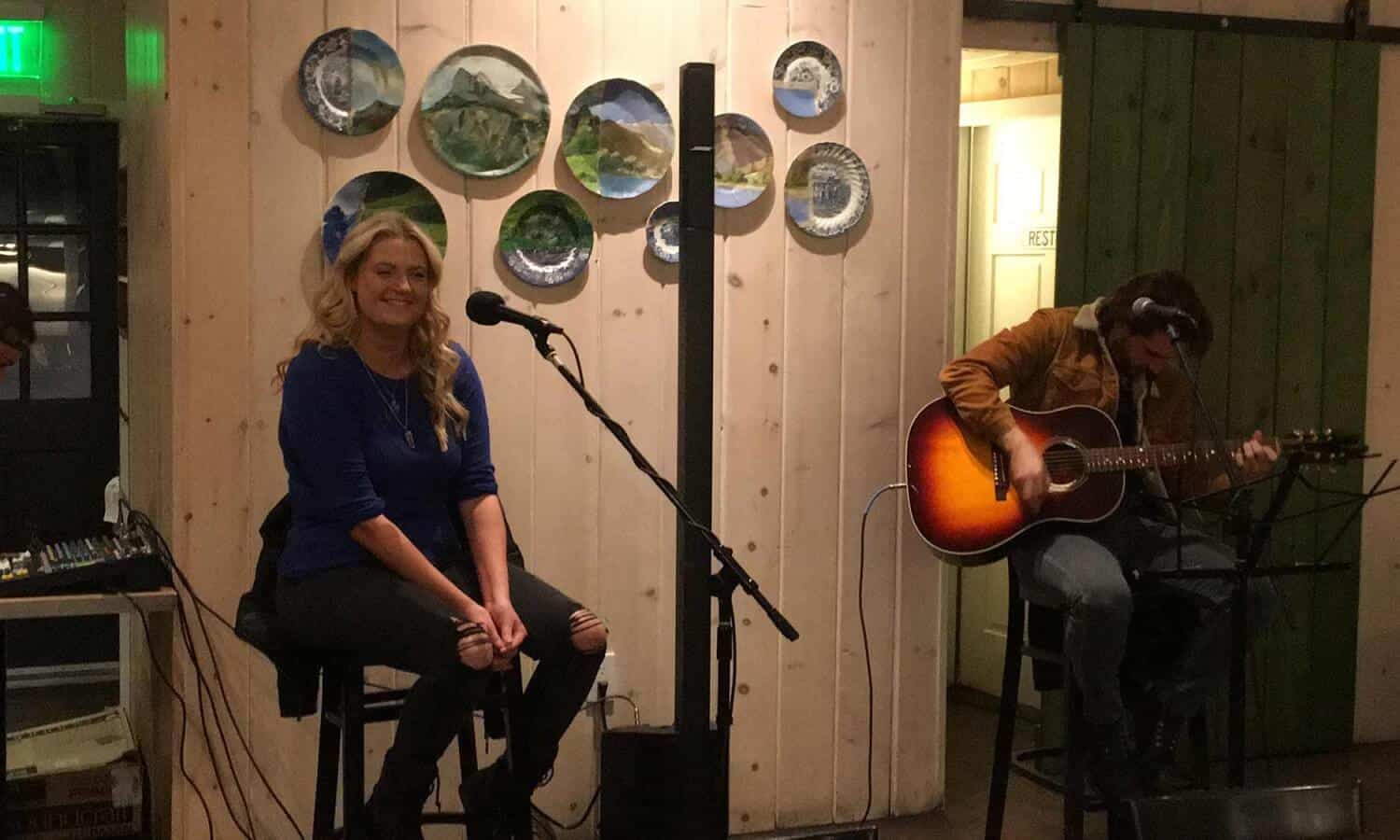 Woman by microphone and man playing guitar Mountainside Treatment Center Alumni Open Mic Night