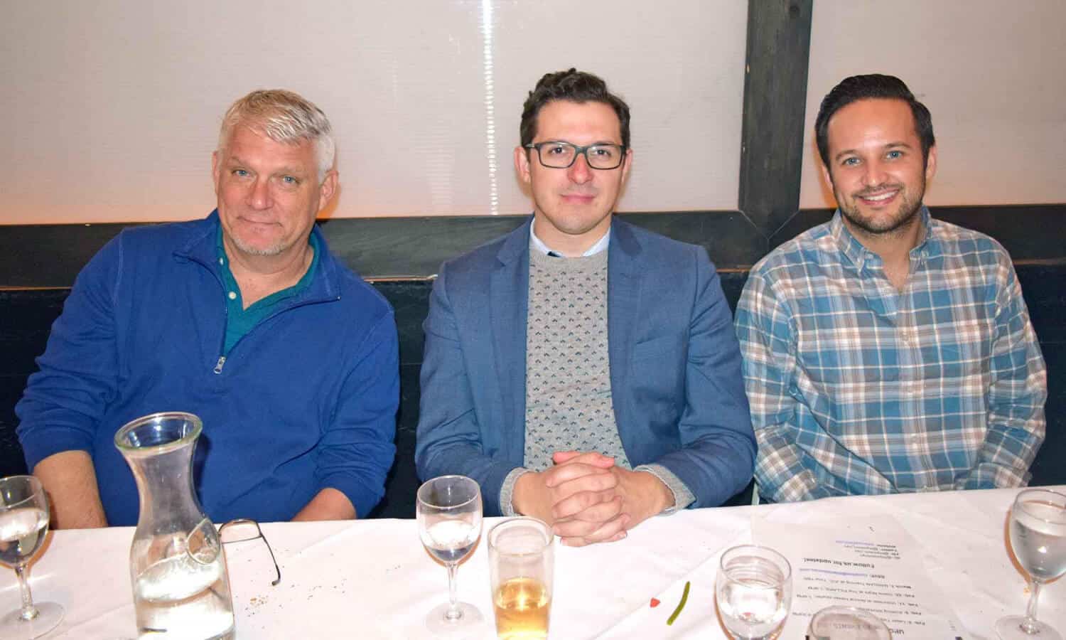 3 men smiling around a table at Mountainside Treatment Center Alumni Dinner and Roundtable in NYC