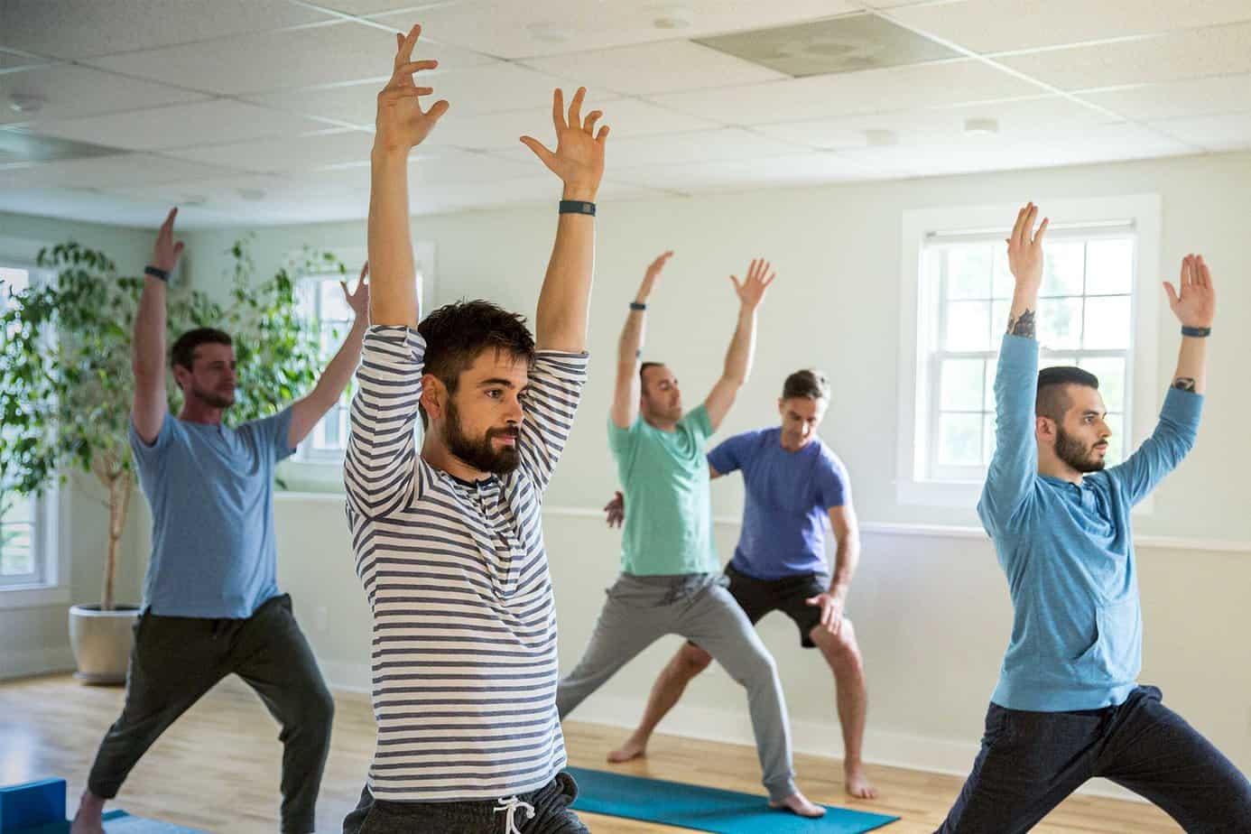 A group of men take a yoga class in bright room at Mountainside