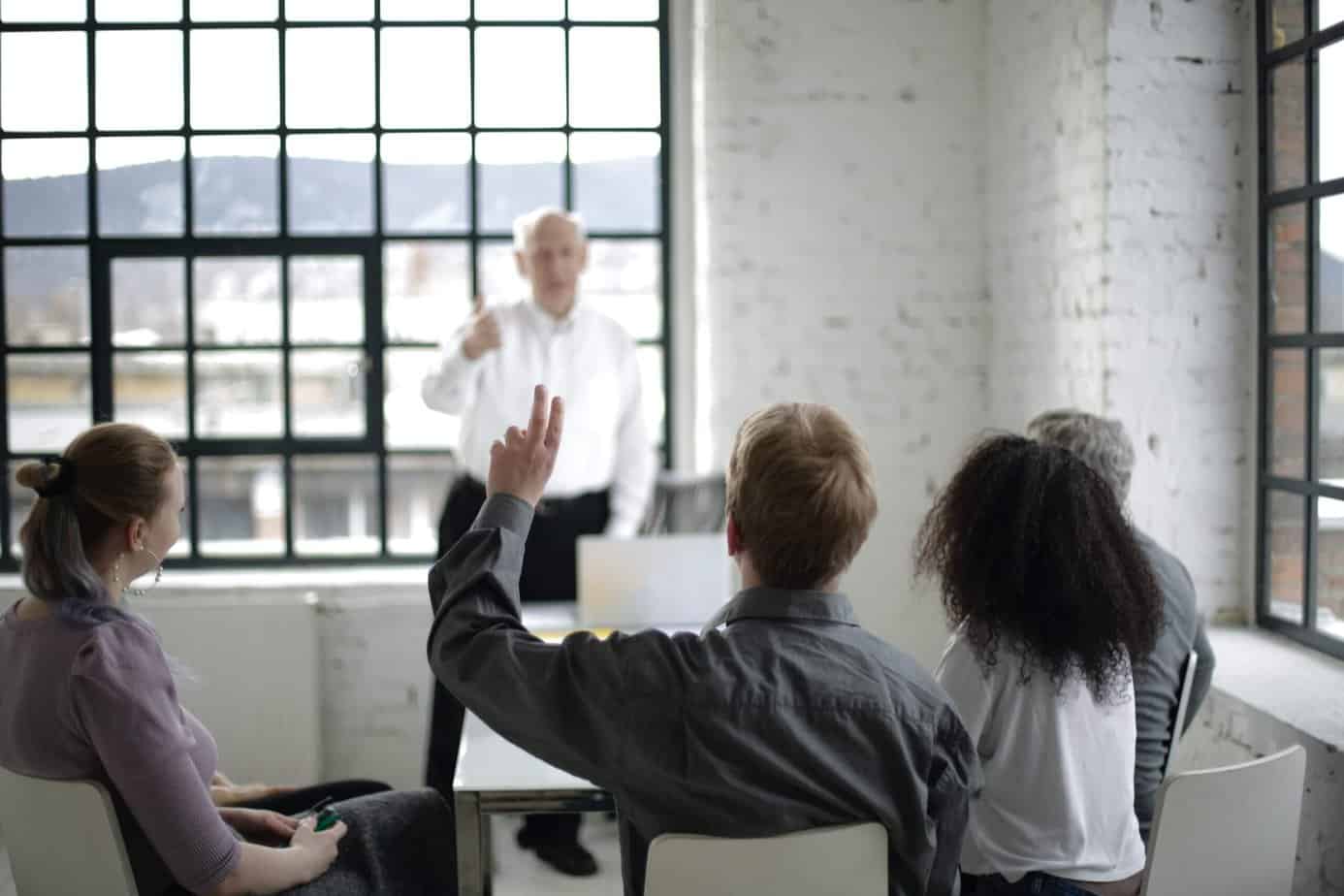 Person raising hand to ask a question - Pexels