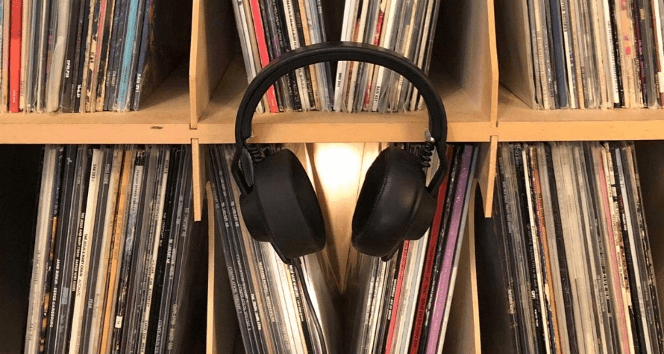 Headphones hanging in front of a wall of records.