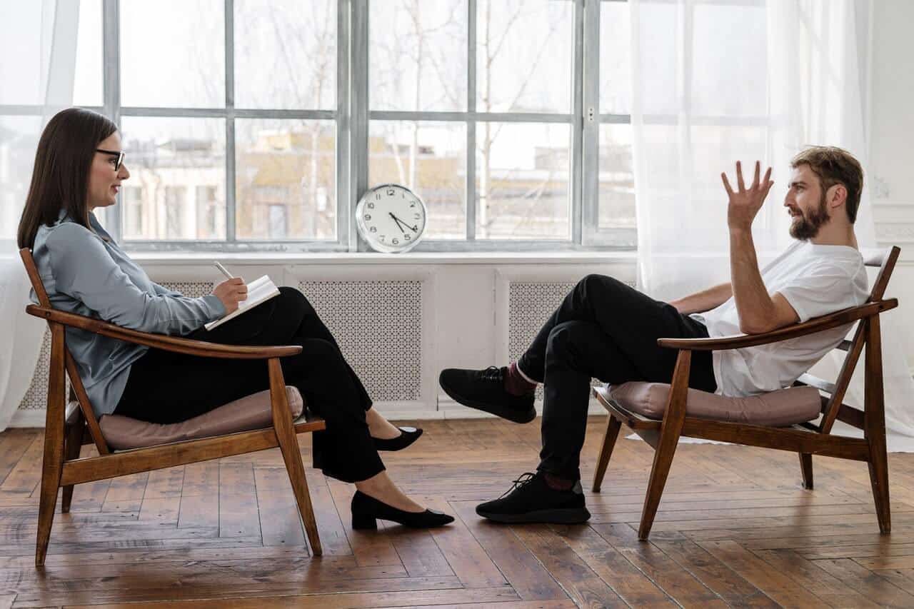 male client and female psychiatrist sit across from each other and discuss aftercare treatment options