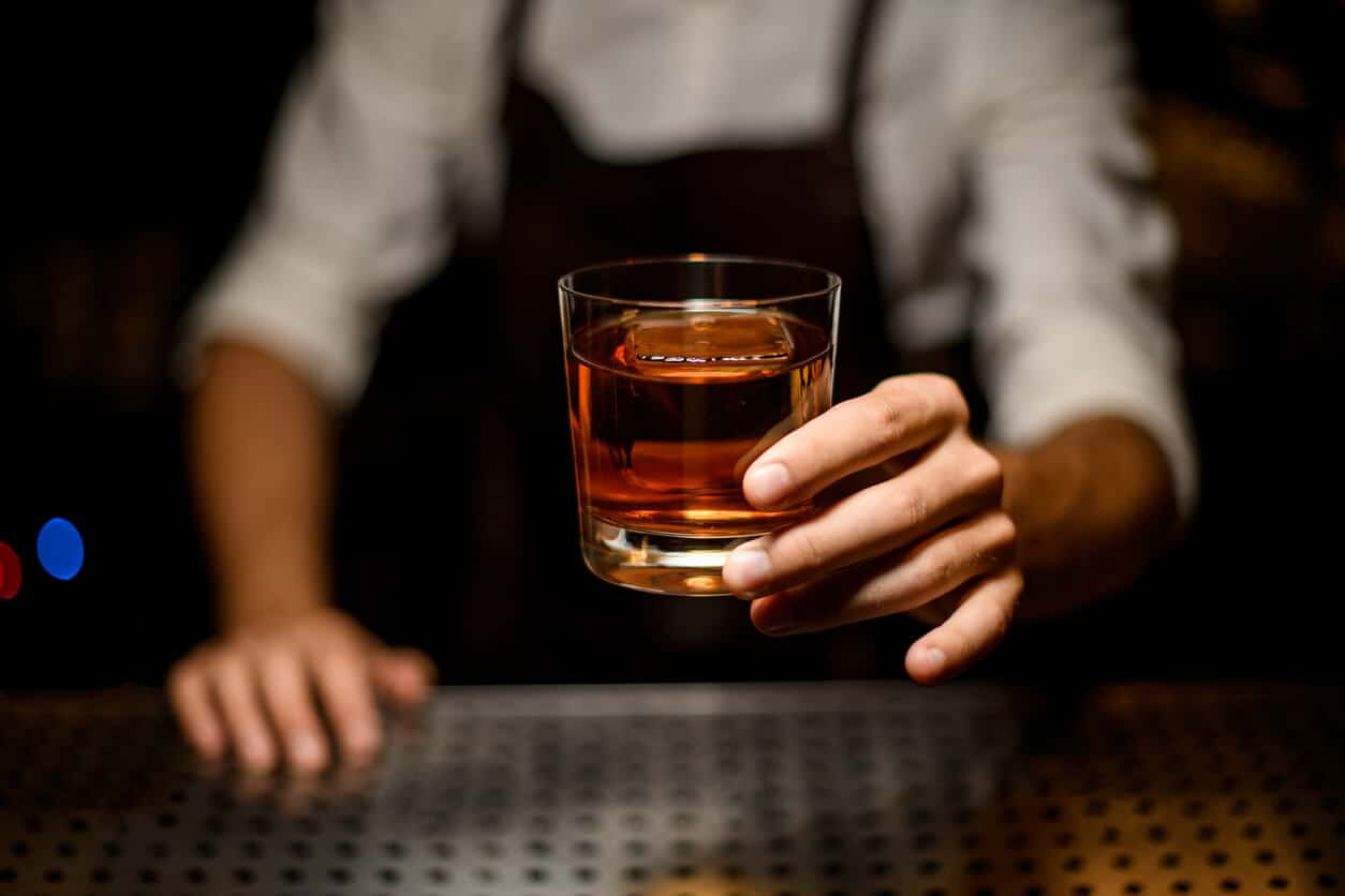 bartender holding out a glass full of liquor