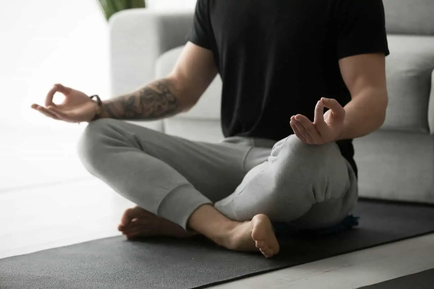 person in athletic clothing sits on floor in yoga pose performing recovery meditation