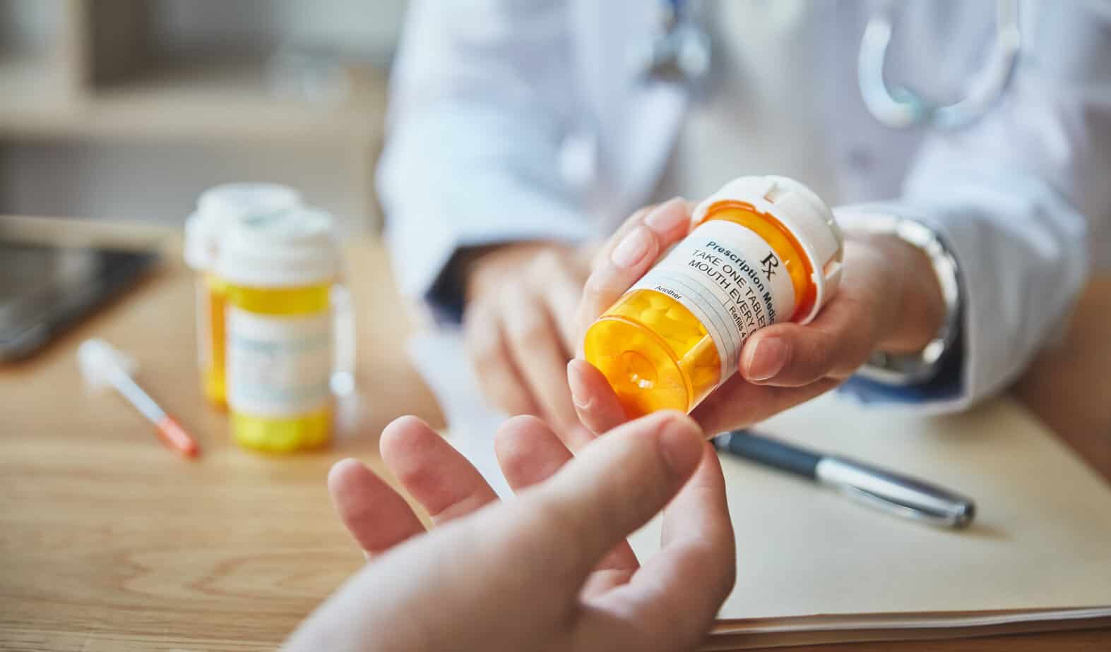 Doctor prescribing pill medication and handing bottle over to patient