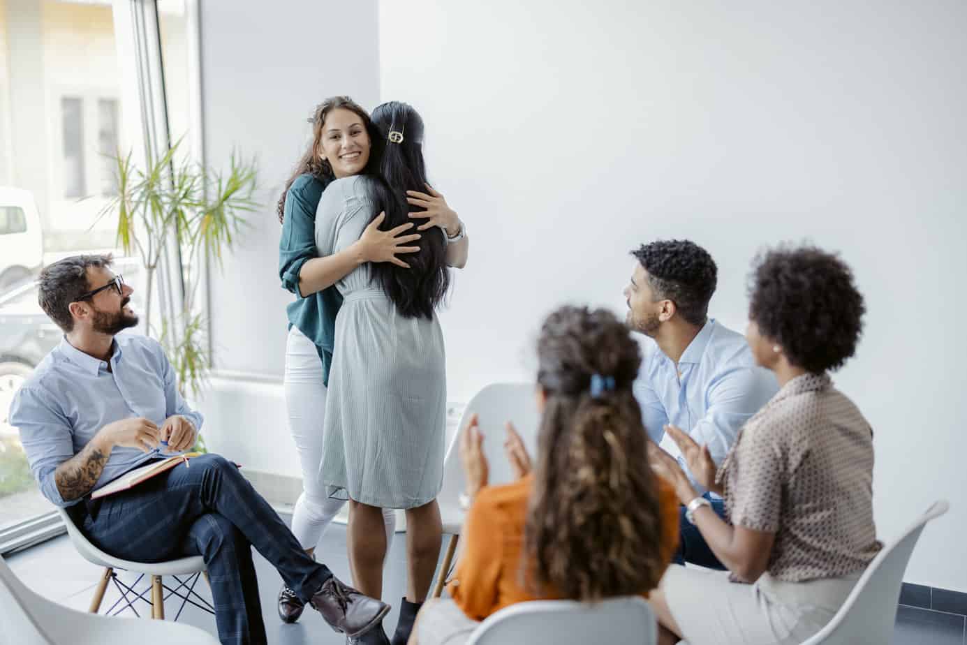 Women embracing giving psychological support during group therapy counseling session, diverse ladies hug sit in circle feel relief empathy helping a friend at with problems addiction