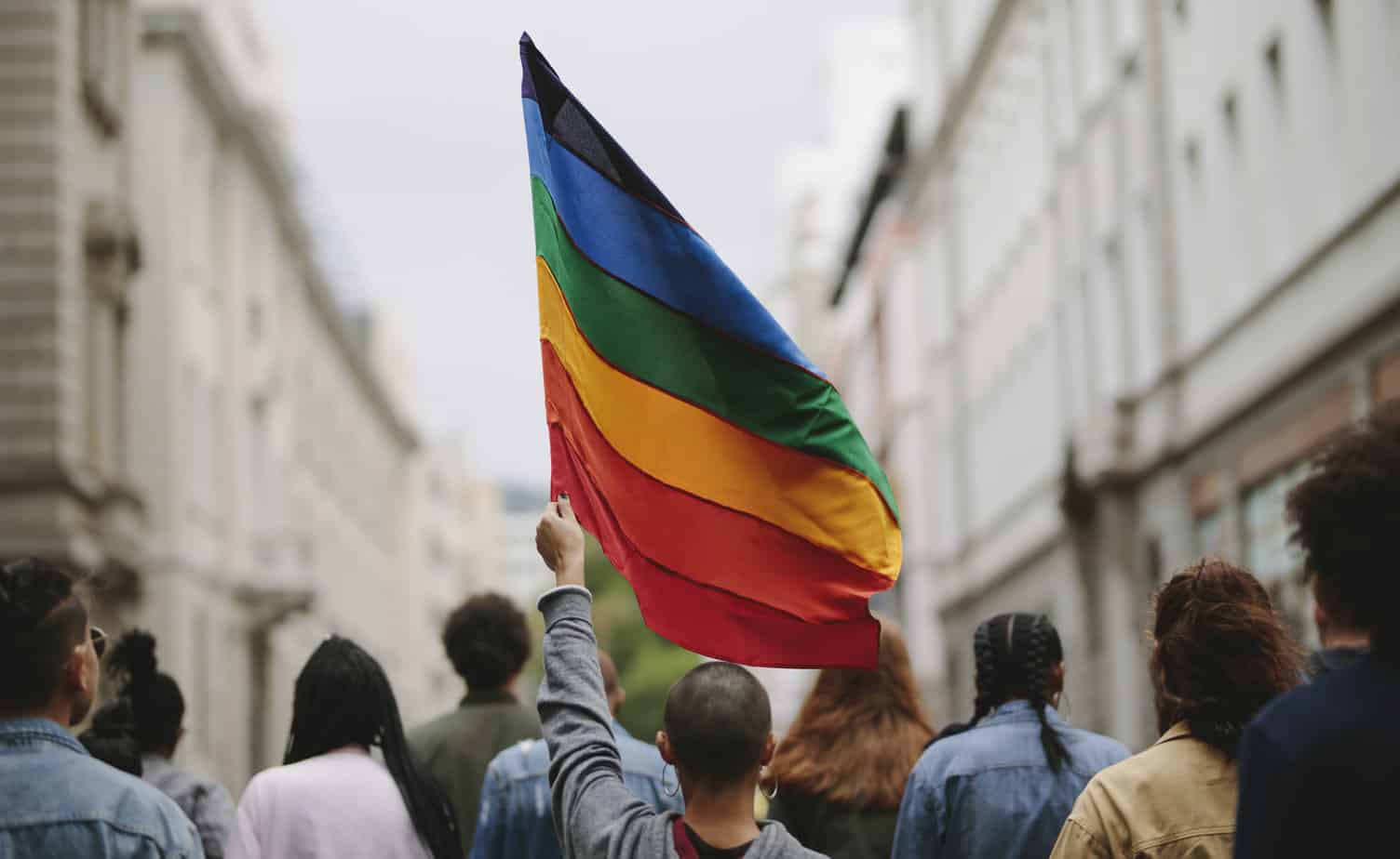 People in a gay pride parade holding flag