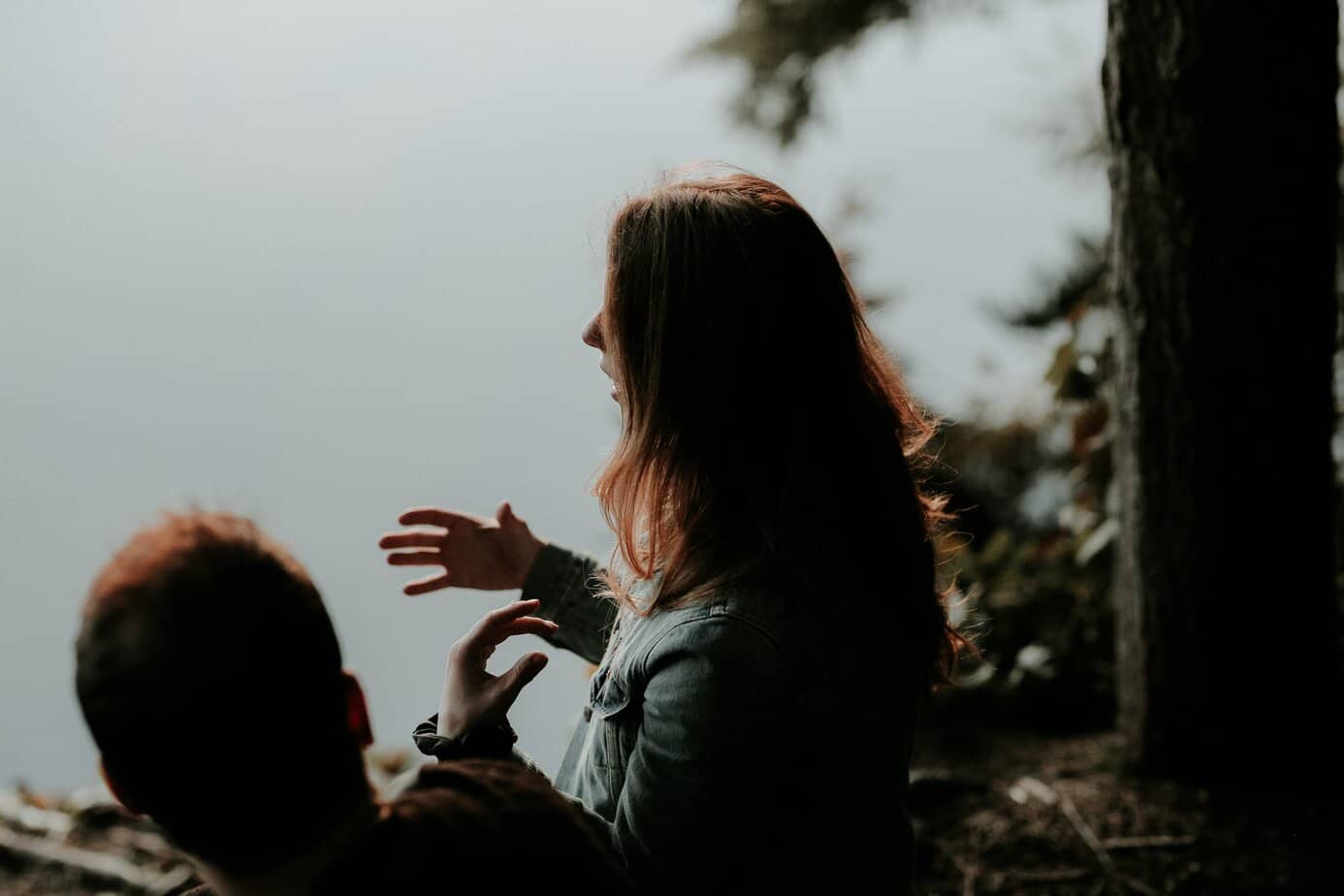 two people stand by the water, hands in motion, and man and a woman, setting boundaries, talking