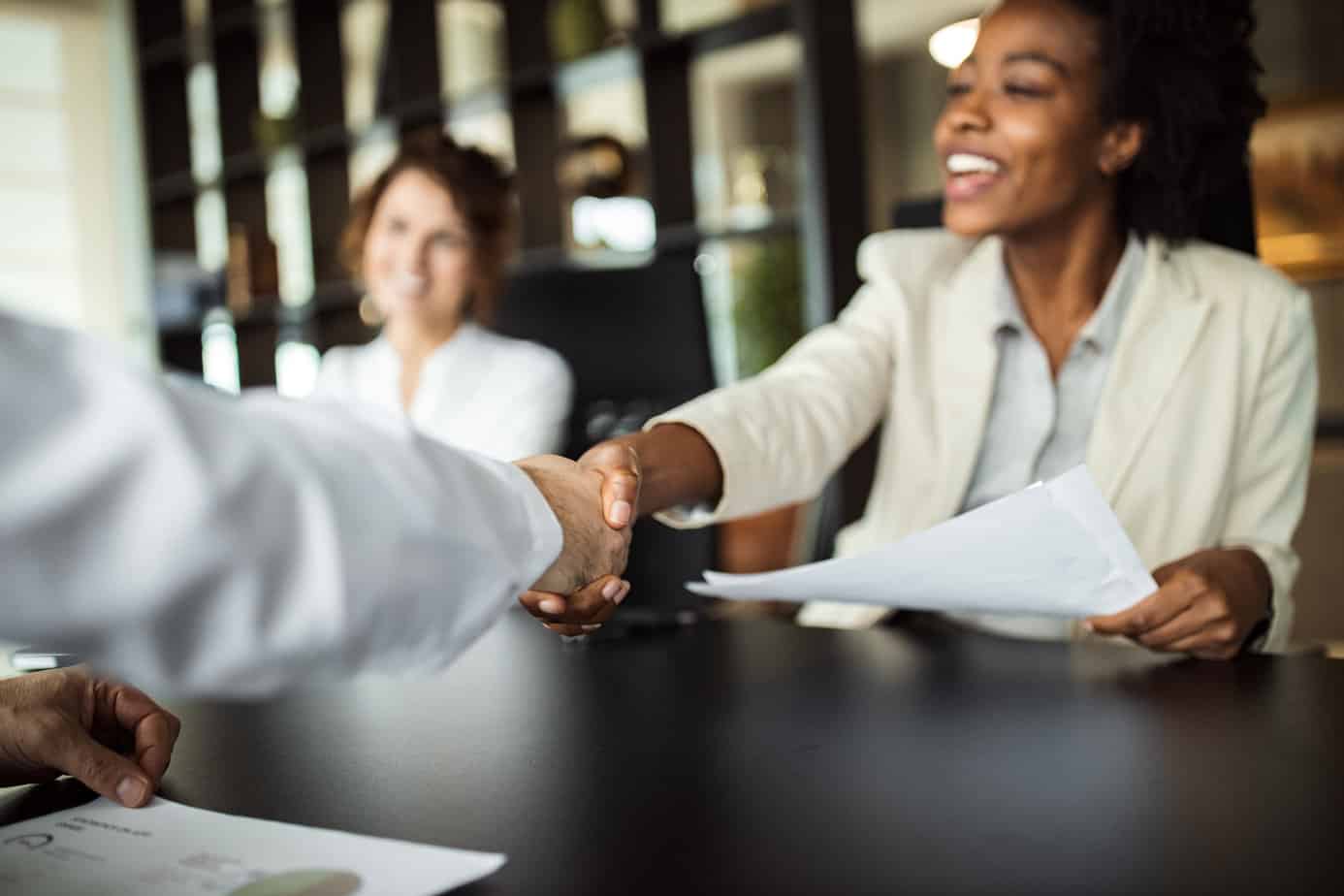 Two people shaking hands at a meeting.