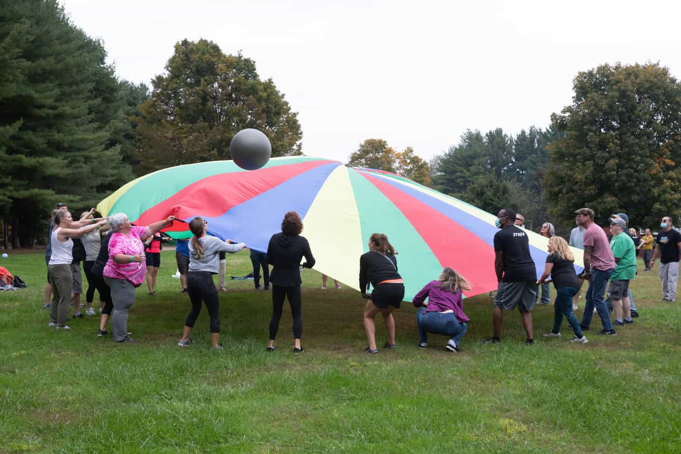 A group of people playing with a parachute on the lawn at Mountainside addiction treatment center.