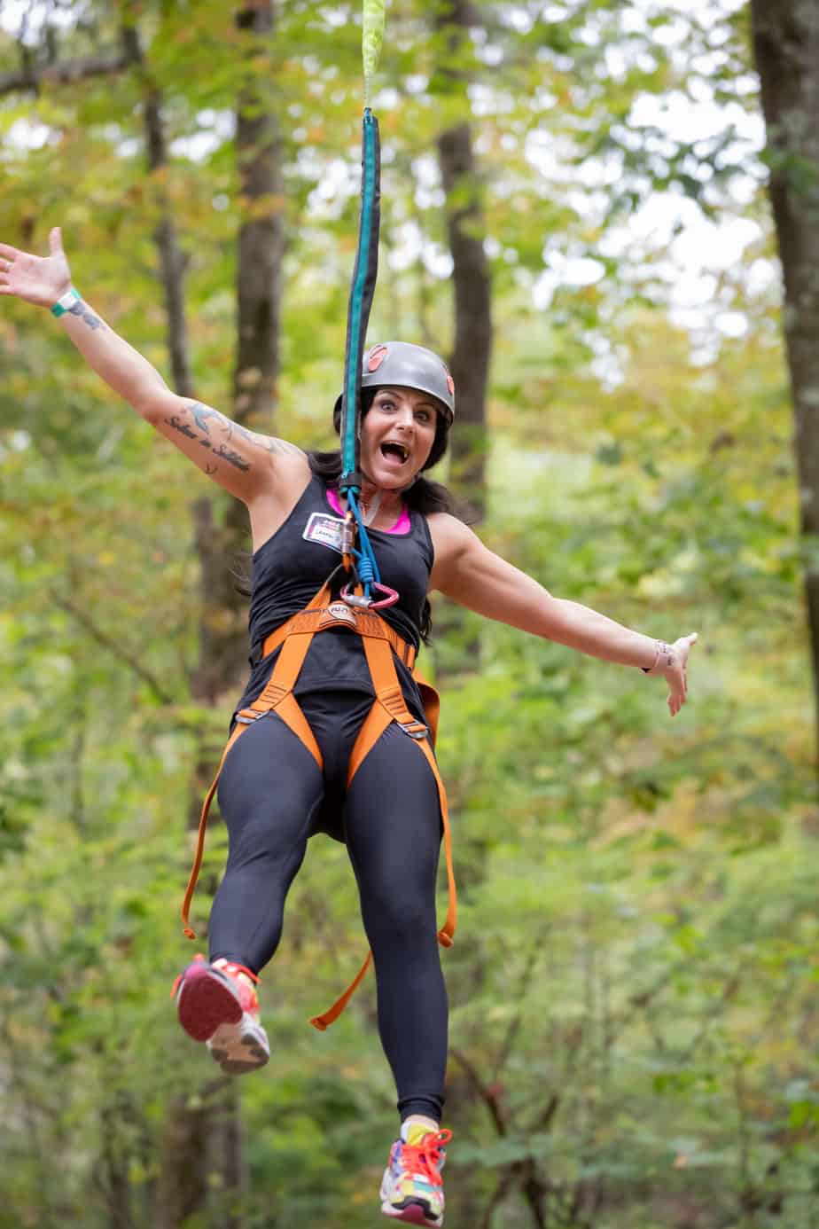 A happy woman ziplining in the woods at Mountainside addiction treatment center in CT.