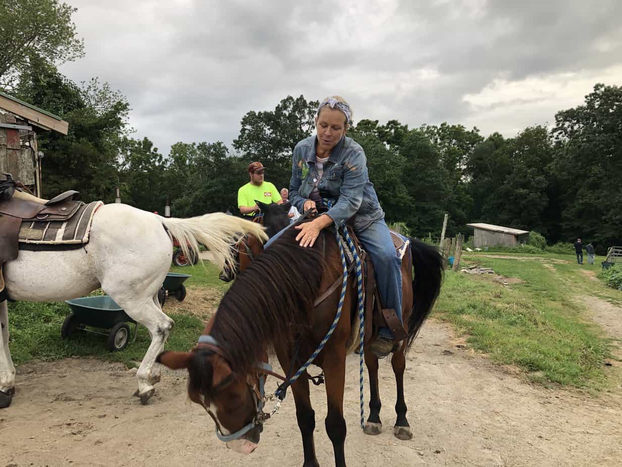 Woman in denim petting horse at Mountainside Treatment Center Alumni Blazing Saddles Event 2021
