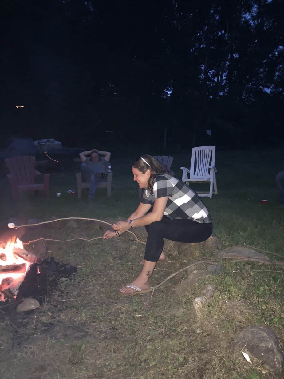 Woman roasting marshmallow around bonfire at Mountainside Treatment Center Alumni Blazing Saddles horseback riding Event 2021