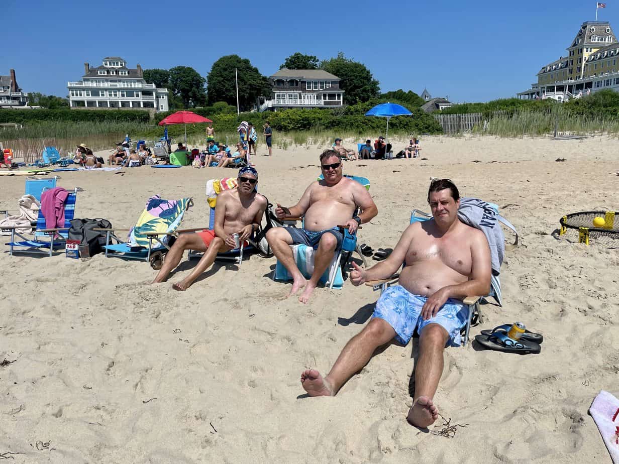 Men on lawn chairs in sand smiling at Mountainside Treatment Center Extended Care at Watch Hill Beach Event July 2021