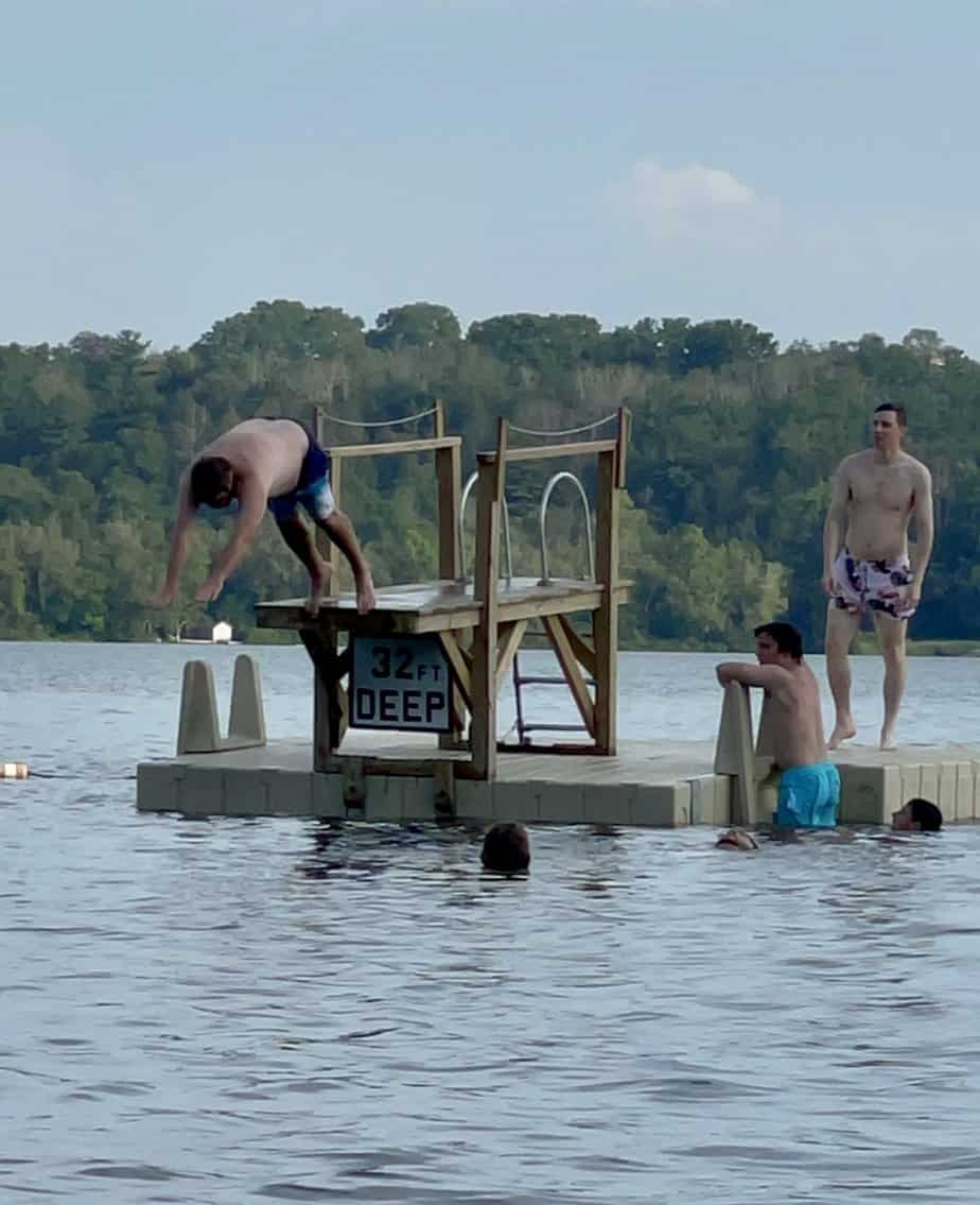 Man Diving into lake while other men swimming outside at Mountainside Treatment Center Extended Care Lakeville Grove Event Summer 2022