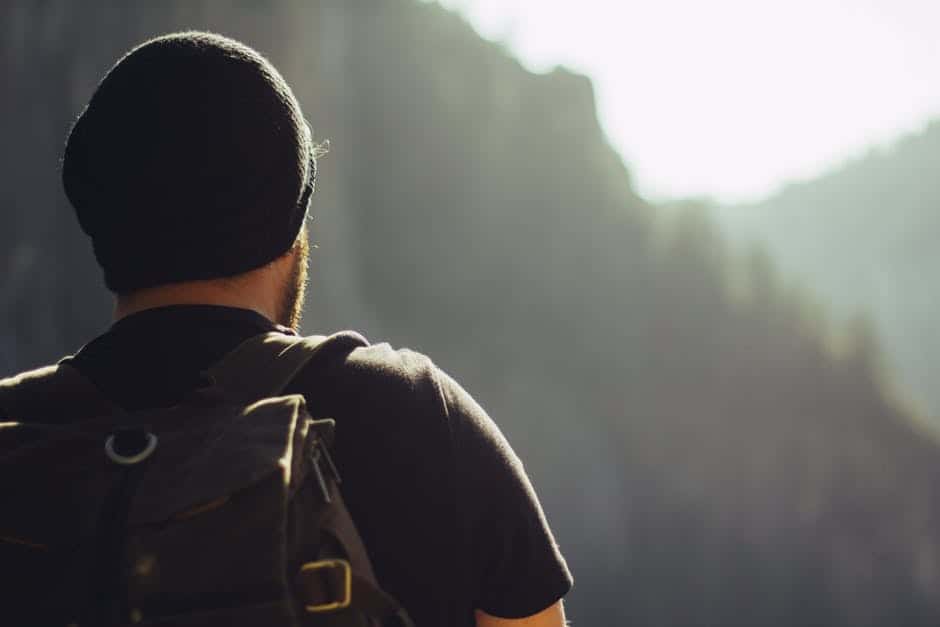 man gazes at forested scenery while hiking in mountains