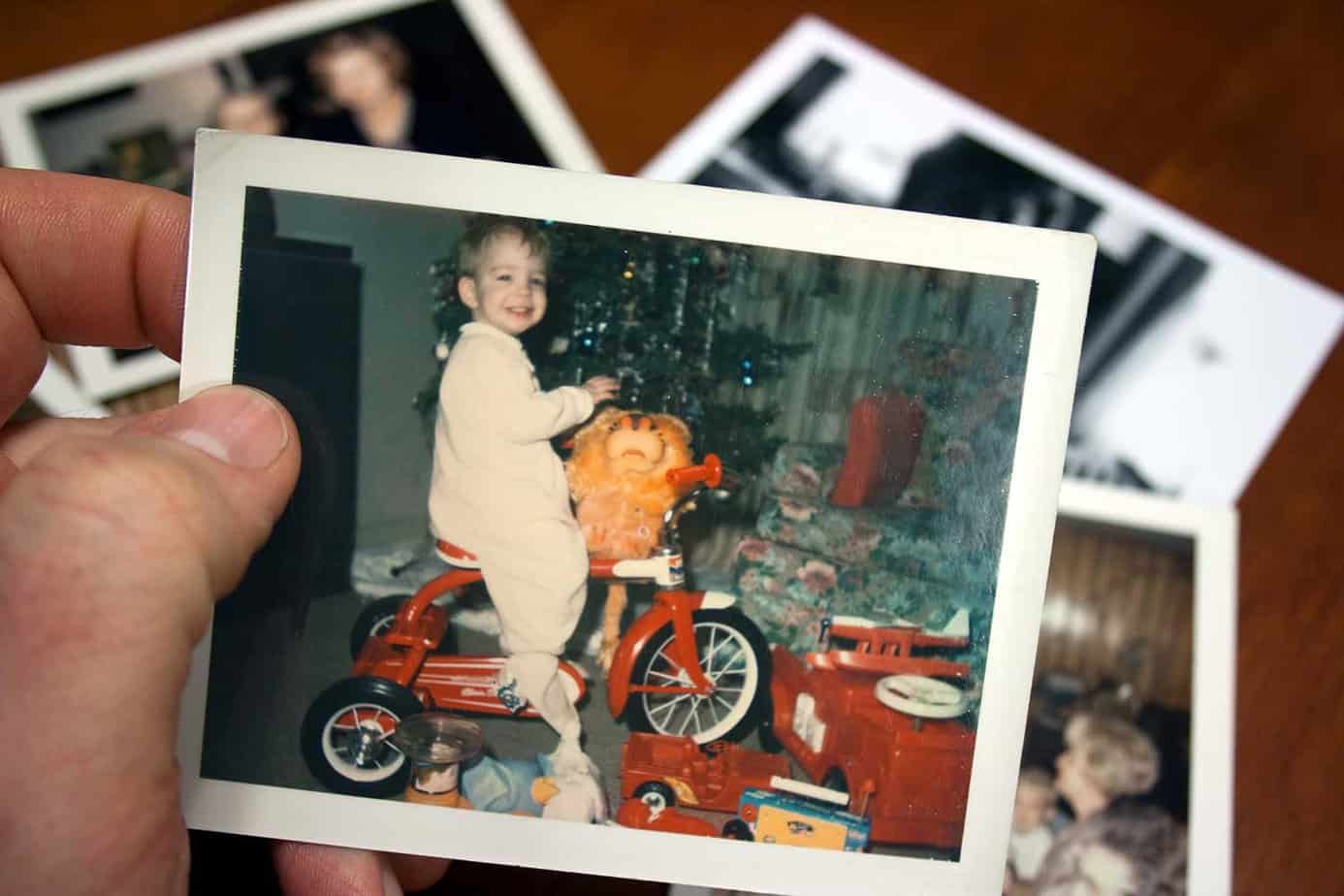 woman holding up old pictures of herself as a child during the holidays