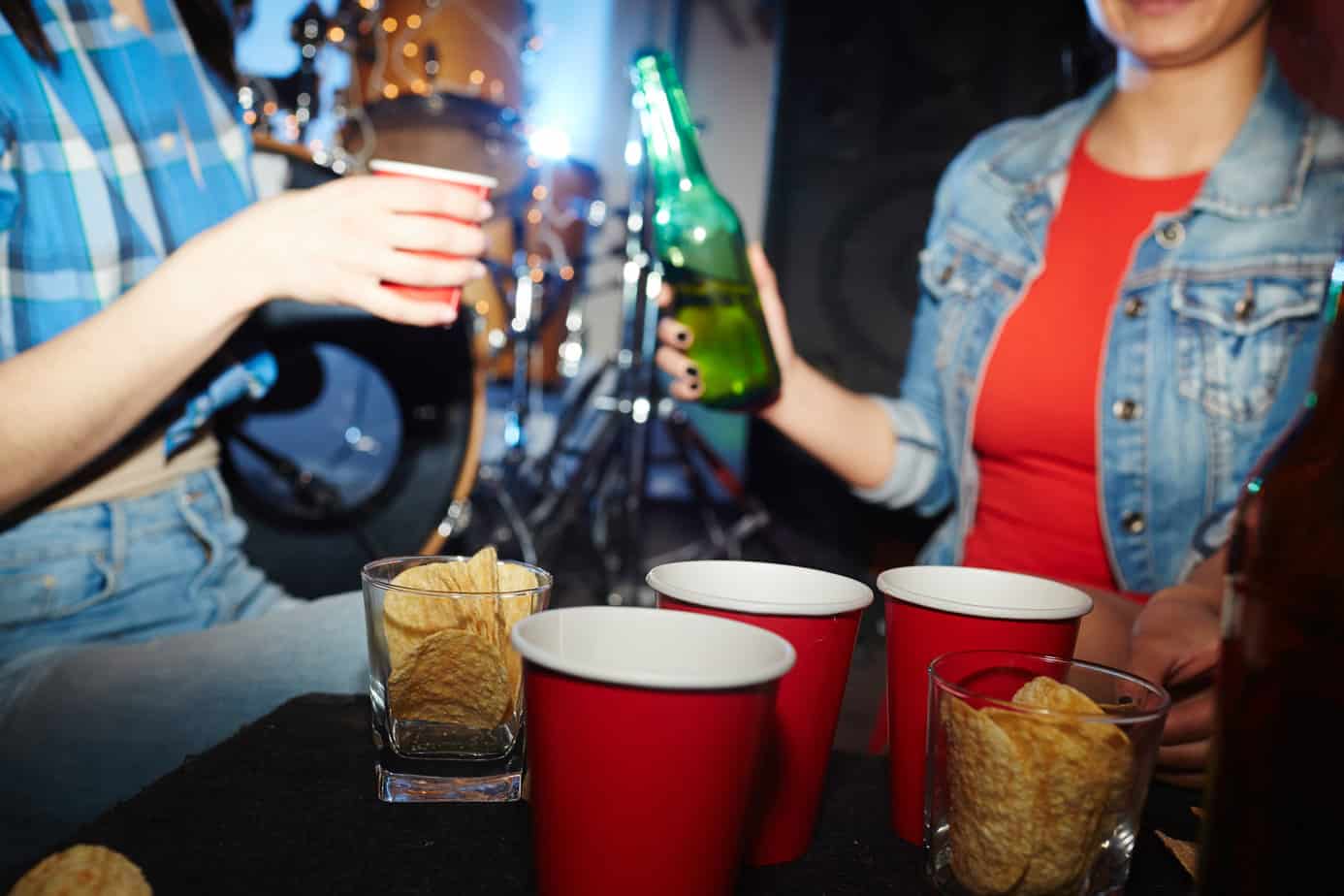 red solo cups and woman holding beer bottle at college party