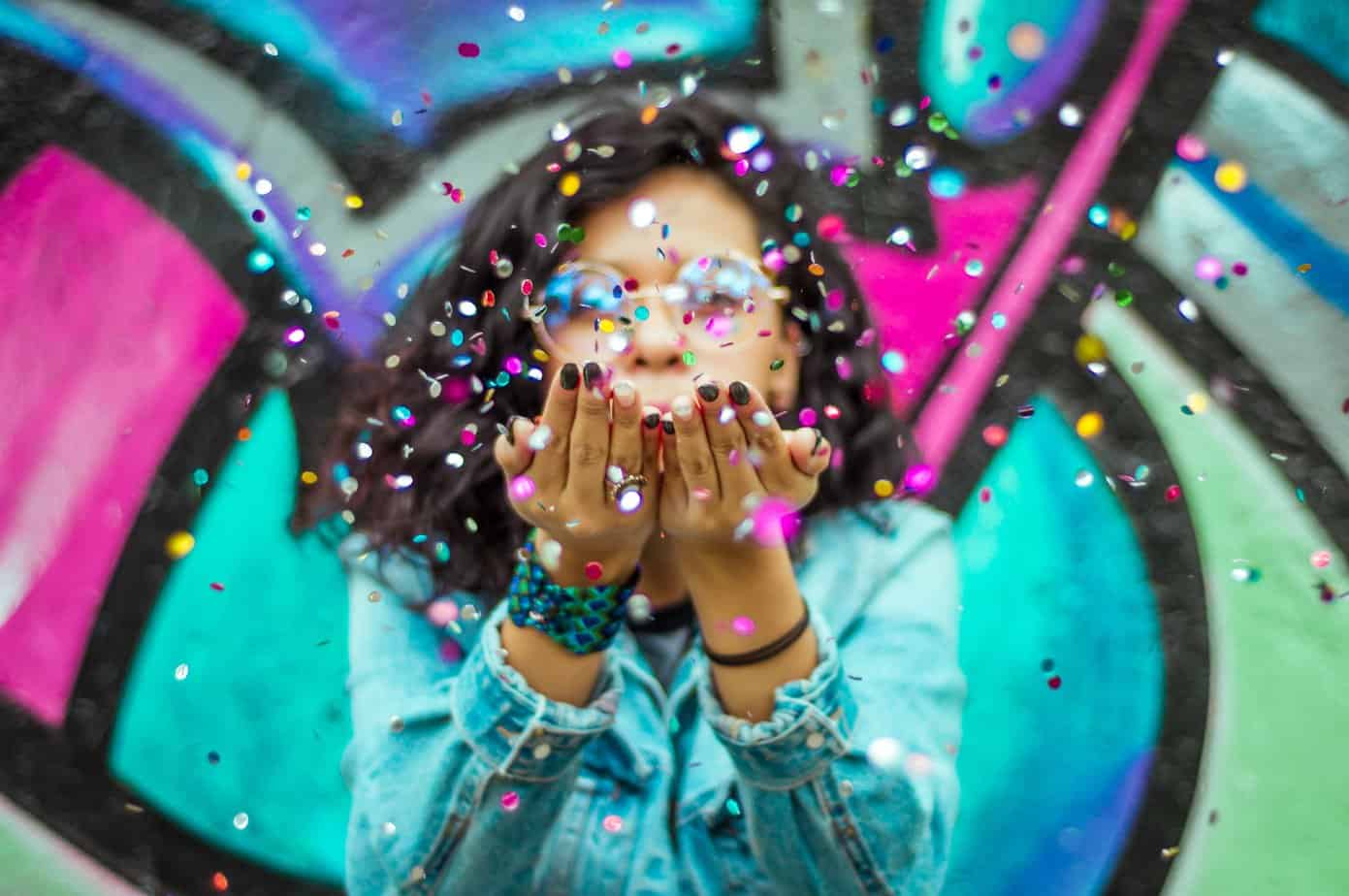 A woman with confetti in front of a graffiti wall, celebrating Recovery Month.