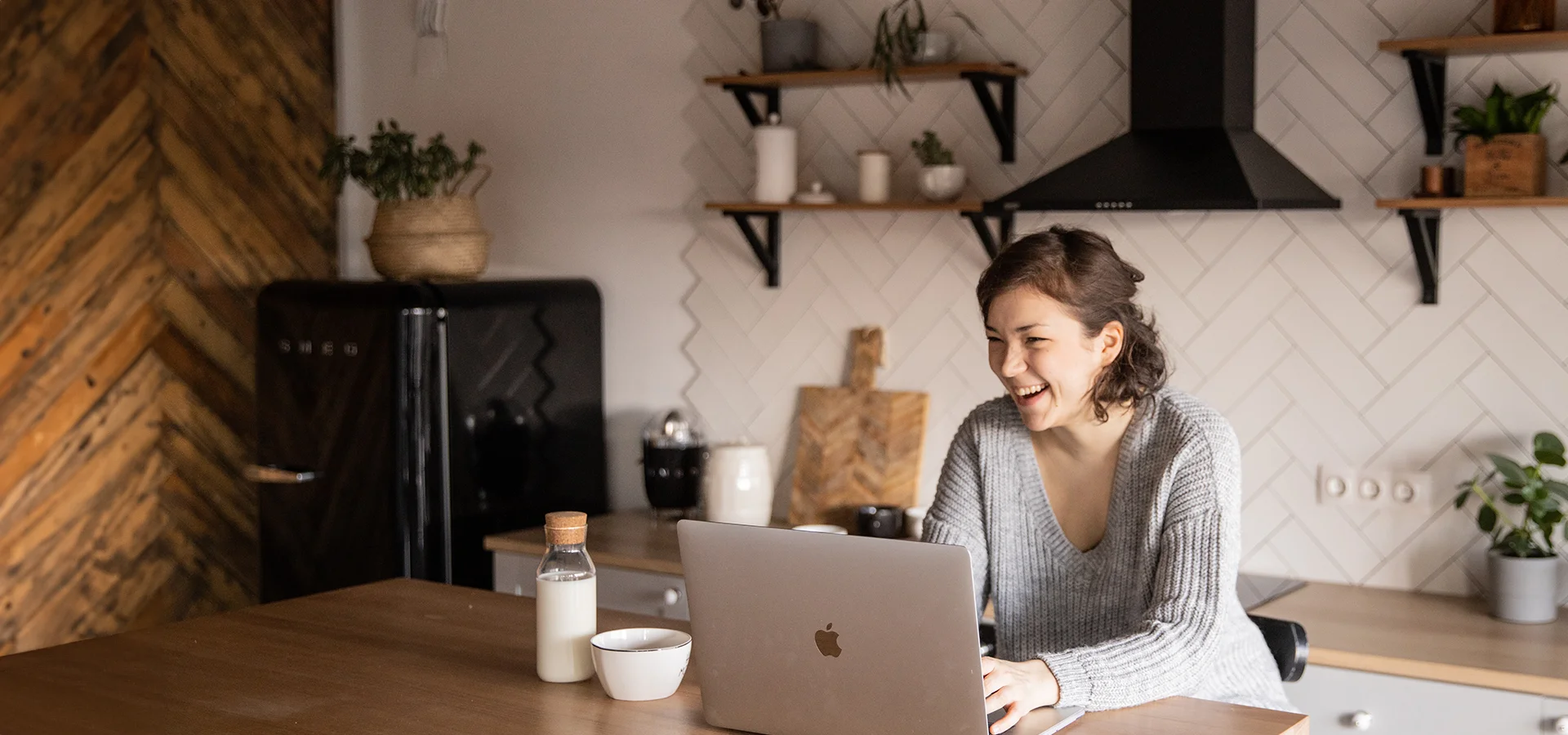 A woman using a laptop computer in her kitchen.