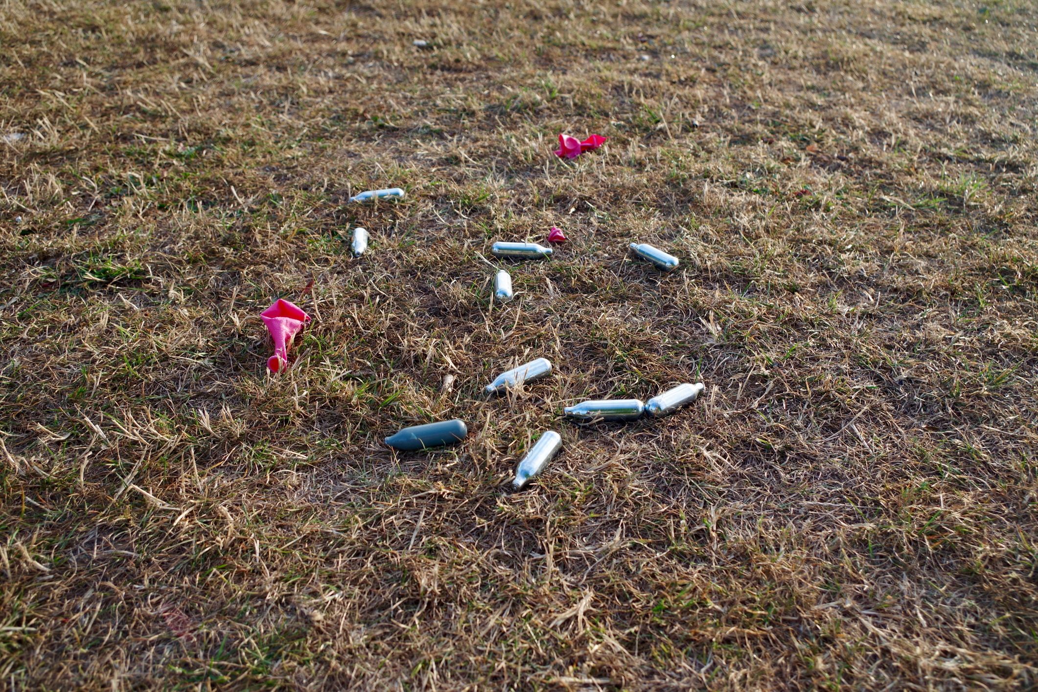 empty nitrous oxide canisters and balloons strewn on the ground