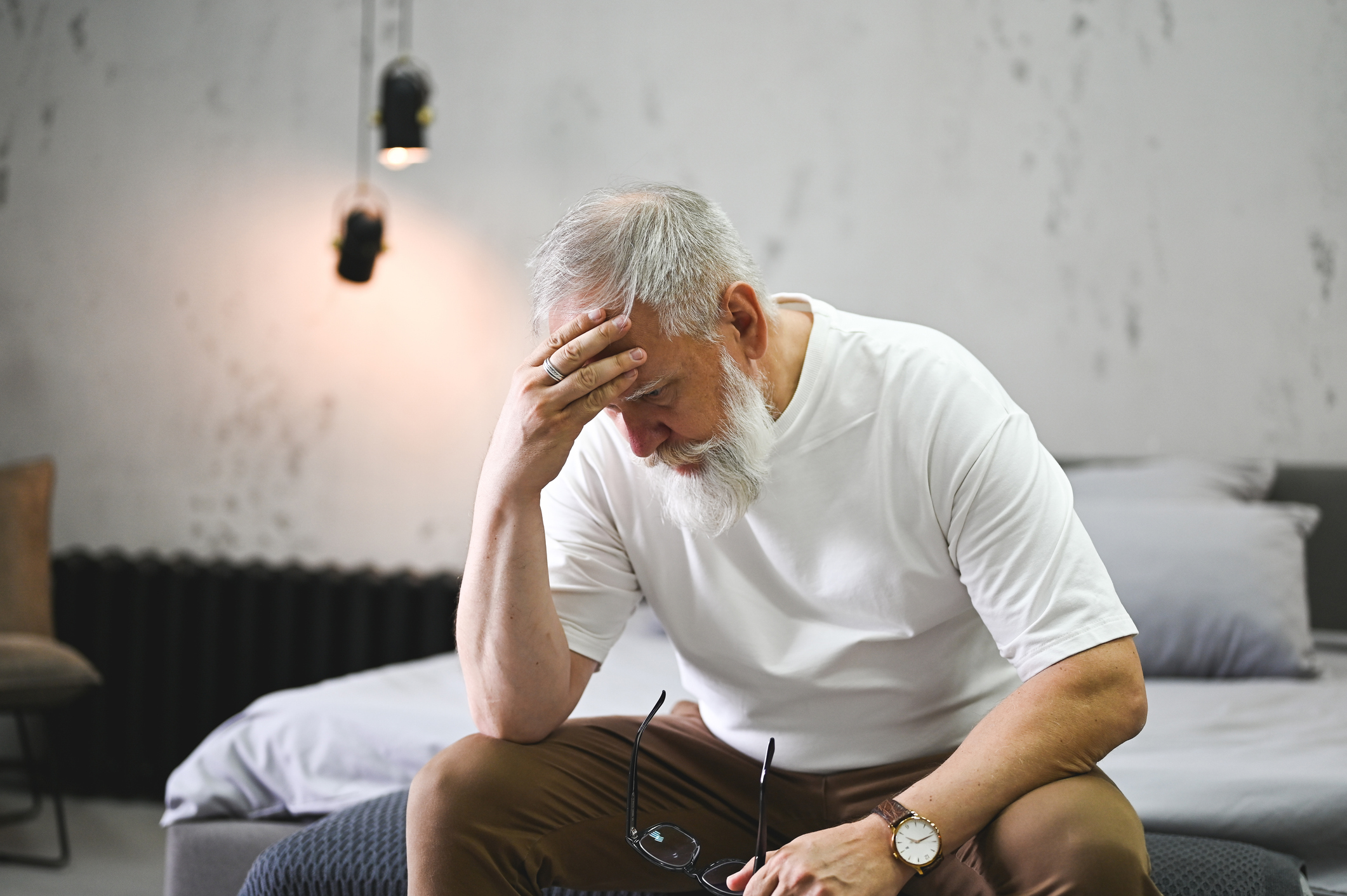 old man sitting on bed and struggling with anxiety and substance use disorders