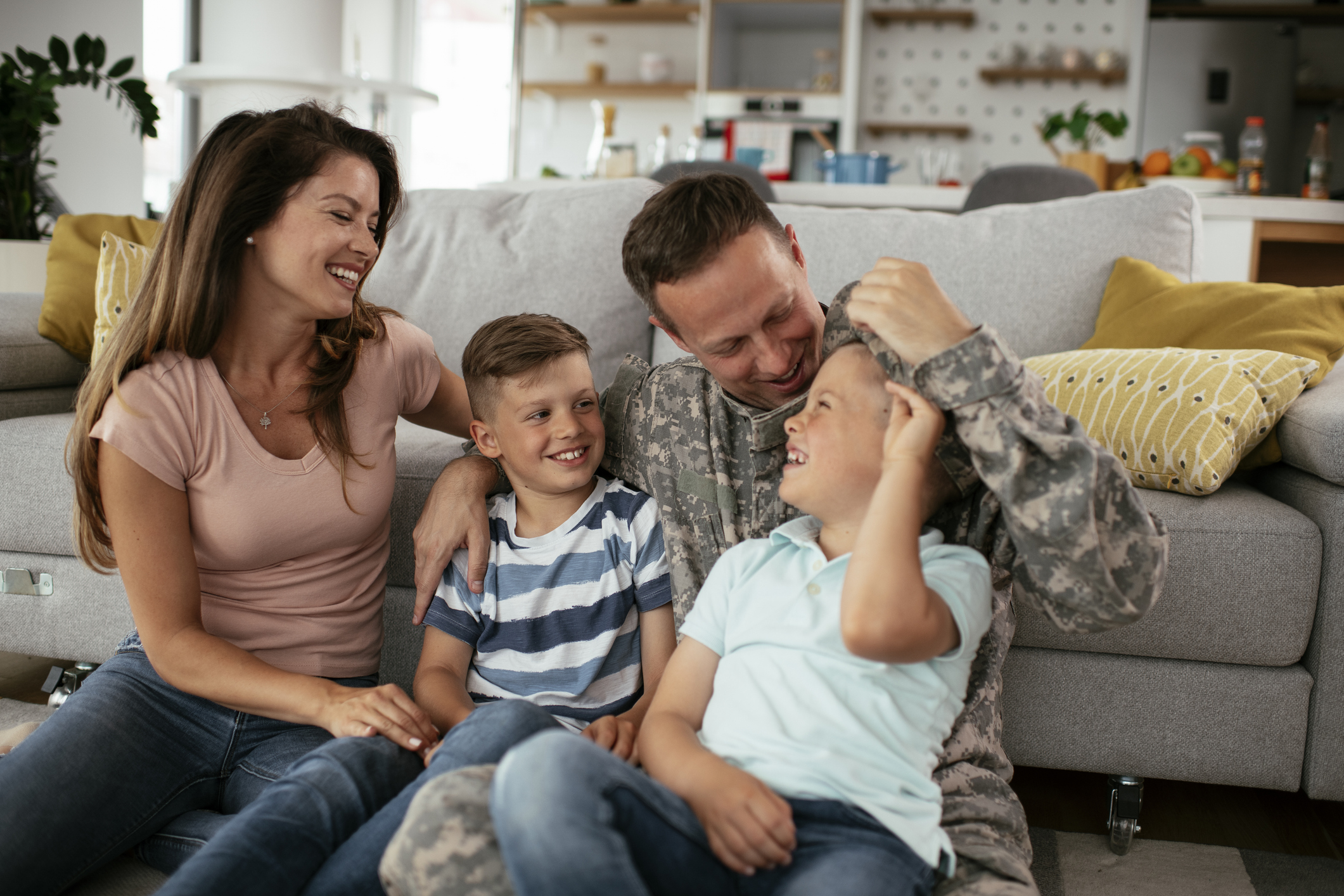 happy veteran man spending time with wife and two children in living room